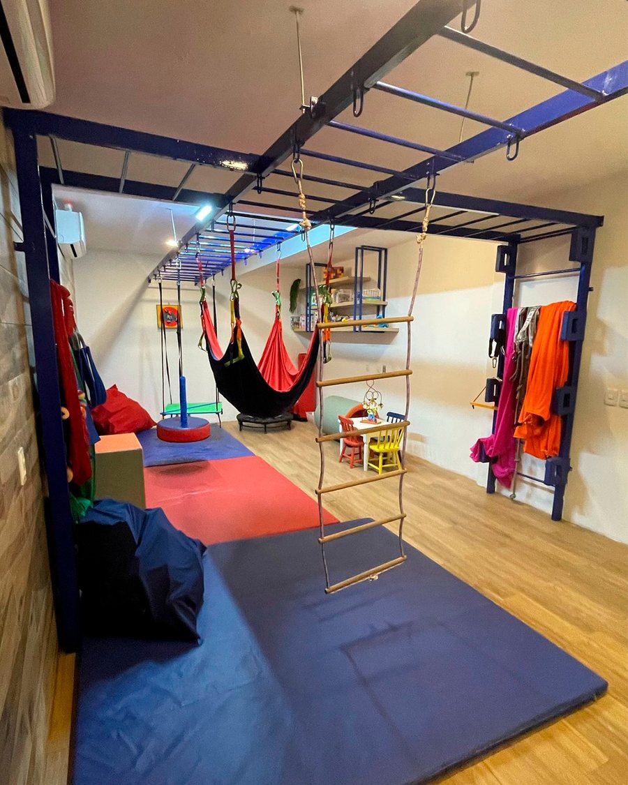 Sala de Integração Sensorial equipada com balanços, escada de corda e colchonetes